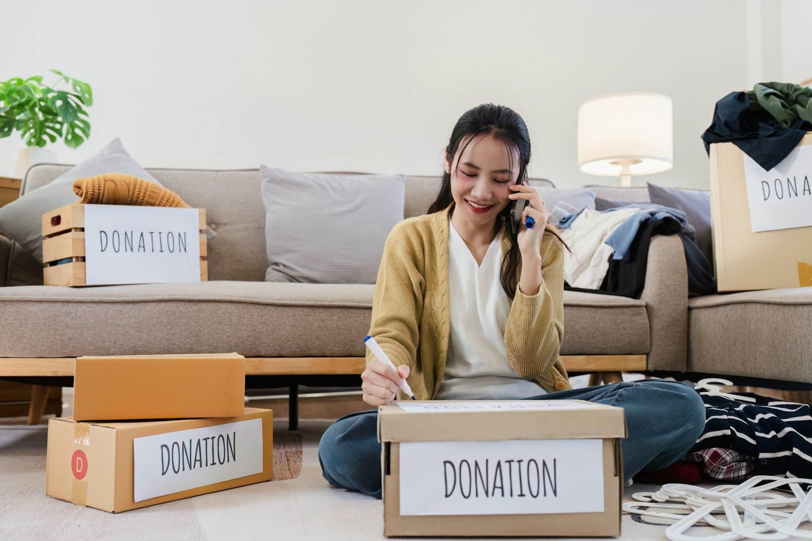 young-woman-asian-of-charity-putting-clothes-in-boxes-with-donations-lettering-and-using-smartphone.jpg